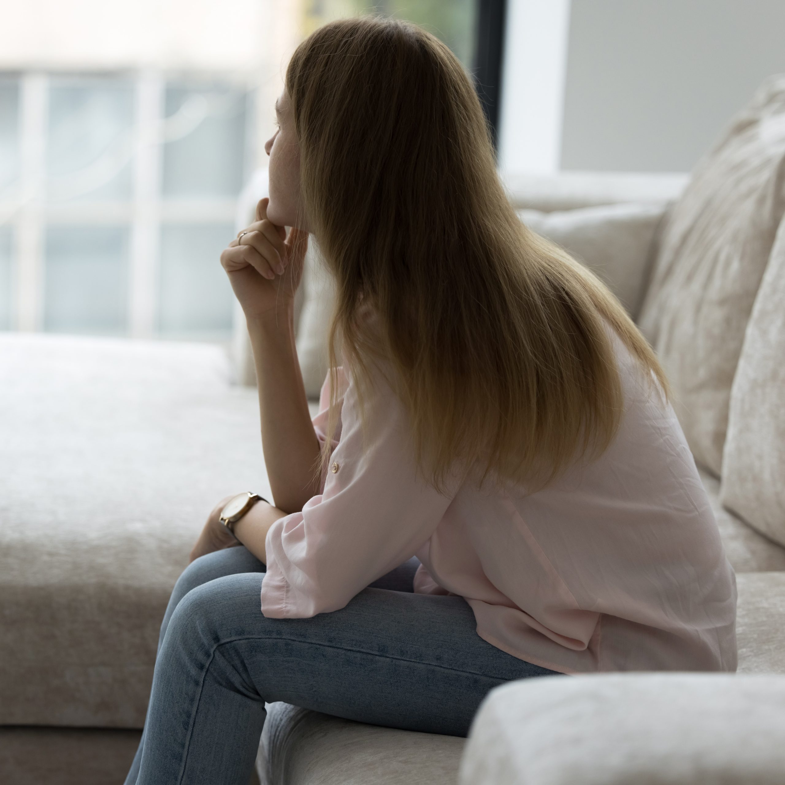 Lonely Woman Sitting On Couch In Living Room, Looking Away